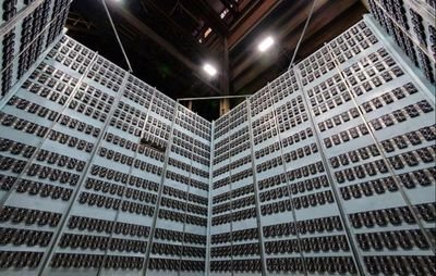 Inside a cryptocurrency mining farm, showcasing rows of mining rigs.